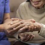 Nurse examining patient's hand to prep for rheumatoid arthritis treatment