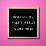 letter board on pink wall that reads "roses are red, violets are blue, cancer sucks" in awareness of metastatic breast cancer month