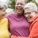 three mature women hugging representing staying healthy at 50 and up