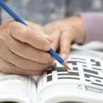 senior person doing a crossword puzzle to prevent dementia risk factors